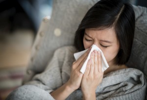 Ill woman with the flu blowing her nose